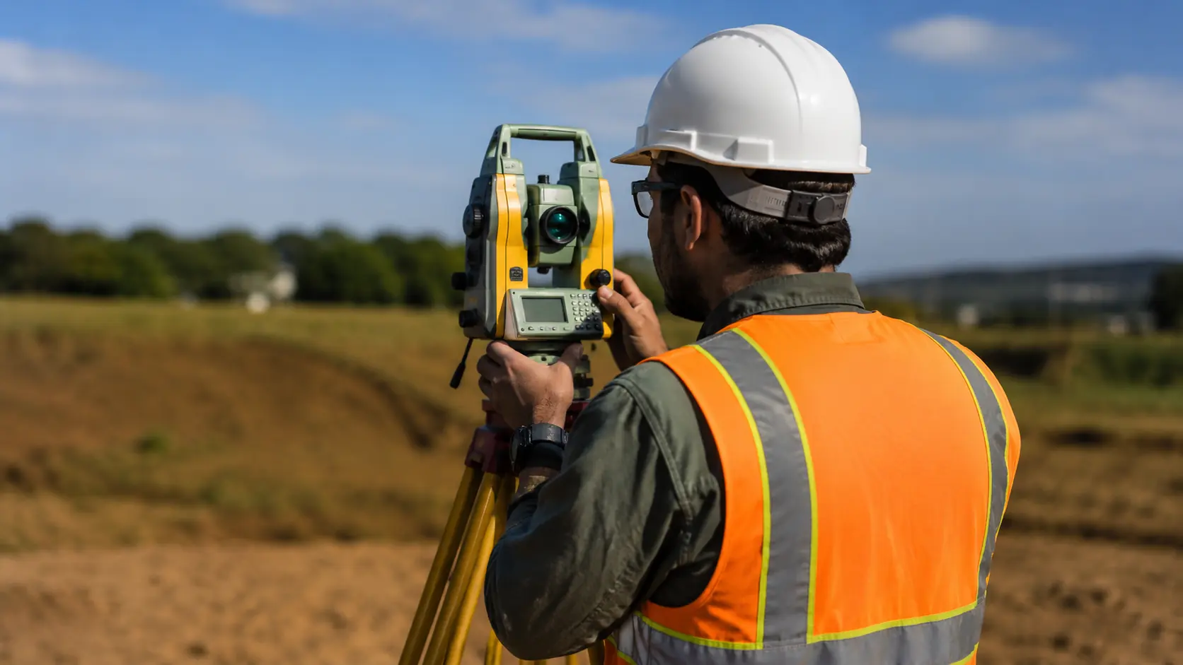 Profissional realizando levantamento topográfico com estação total em campo